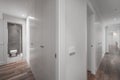 Long hallway with cabinet lined walls, corner cloakroom with open door