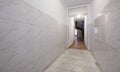 Long hallway leading to a house with marble floors and stoneware tiled walls with access to internal wooden stairs Royalty Free Stock Photo