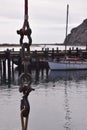 Long hanging metal chain link with an old boat docked at the pier with Morro Rock in the distance Royalty Free Stock Photo