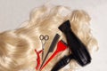 Long healthy blond hair and professional scissors, comb and hair dryer, top view Royalty Free Stock Photo