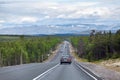 Long highway stretches away to mountains on horizon. Cars driving on asphalt road the Kola. It is way to the Murmansk city on
