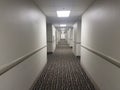 long hotel hall with brown carpet and white walls