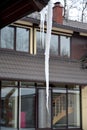 The long icicle which is dangerously hanging down from a roof