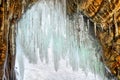 Long icicles on arch of small grotto in coastal rock Royalty Free Stock Photo