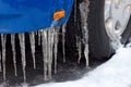 long icicles on a blue car, symbol for freezing rain