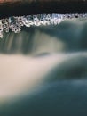 Long icicles hang above dark freeze water of mountain stream. Royalty Free Stock Photo