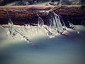 Long icicles hang above dark freeze water of mountain stream. Royalty Free Stock Photo