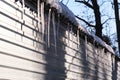 Long icicles hang from roof house.On a sunny spring day.