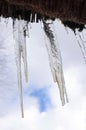 Spring icicles on the roof against cloudy sky Royalty Free Stock Photo