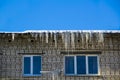 Long icicles and snow hang on the eaves of the house roof Royalty Free Stock Photo