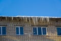 Long icicles and snow hang on the eaves of the house roof Royalty Free Stock Photo