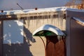 Long icicles and snow hang on the eaves of the house roof Royalty Free Stock Photo