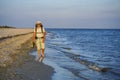 A tourist guy with a large backpack, dressed in shorts, a Panama T-shirt and glasses, walks along the wet sand along the sea coast Royalty Free Stock Photo