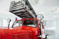 Long ladder is an indispensable part. Front of the red polished fire truck standing indoor at exhibition