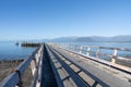 Long leading and converging lines and shadows of pier projecting into bay under blue sky Royalty Free Stock Photo