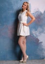 Long legged blonde girl in white stockings posing at the wall