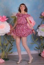 Long legged brunette girl in white fishnet stockings and minidress posing at the flowers Royalty Free Stock Photo