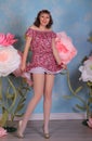 Long legged brunette girl in white fishnet stockings and minidress posing at the flowers Royalty Free Stock Photo