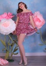 Long legged girl in red minidress and white fishnet stockings posing at the flowers Royalty Free Stock Photo