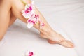 Long legs of a woman with a fresh manicure and orchid flowers Royalty Free Stock Photo