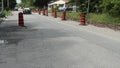 long line row of orange and black traffic delineator pylon barrel drums at side