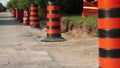 Long line row of orange and black traffic delineator pylon barrel drums