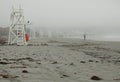 Misty day on the beach with white wooden lifeguard stations Royalty Free Stock Photo