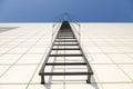 Long metal staircase on the gray modern facade of an industrial building, warehouse or shopping center against the blue sky. Fire Royalty Free Stock Photo