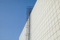 Long metal staircase on the gray modern facade of an industrial building, warehouse or shopping center against the blue Royalty Free Stock Photo