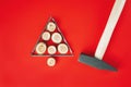 Long nails and wood cuts or branch slabs, laid out in shape of Christmas tree with hammer on red background, flat lay
