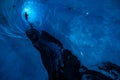 Long narrow ice cave in a glacier in remote Alaska. Man stands in the back under a thin section of ice with light shining through Royalty Free Stock Photo