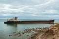 A long old ship wrecked on the Russian coast. The rusty drydocker was nosed against the shore and tilted.