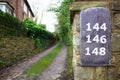 Long Overgrown Pathway With Slate Numbers On A Wall