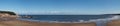 Panoramic view of the beach at Scarborough south bay on a sunlit summer day with the town harbour and lighthouse in the Royalty Free Stock Photo