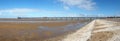 Long panoramic view of southport pier from the beach with blue shy reflected in water on the beach at low tide Royalty Free Stock Photo