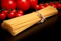 Long pasta raw isolated on black table with tomatoes