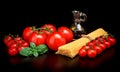 Long pasta raw isolated on black with tomatoes and olive oil