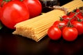 Long pasta raw isolated on black with tomatoes and olive oil