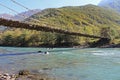 Long pedestrian suspension bridge over the mountain river Bzyb on a sunny autumn day in Abkhazia Royalty Free Stock Photo
