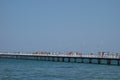 Long pier ino the sea, with lots of people walking on it