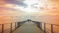 Long pier over the sea shore, evening autumn light leak, sihouette of walkers Royalty Free Stock Photo