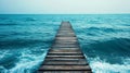 A long pier stretching into the ocean with gentle waves lapping below Royalty Free Stock Photo