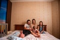 Long range shot of beautiful family on the bed in the morning in the sun from window. General view