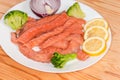Long raw salmon slices among the vegetables and lemon slices Royalty Free Stock Photo
