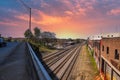 A long red brick building near the railroad tracks covered with colorful graffiti with powerful red clouds in the sky at sunset Royalty Free Stock Photo