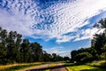 A long road under a blue sky with lots of white clouds Royalty Free Stock Photo