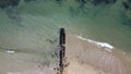 Long, rocky wave breaker on the beach with calm waves crashing against it on a Summer`s day at Point Lonsdale, Mornington