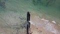 Long, rocky wave breaker on the beach with calm waves crashing against it on a Summer`s day at Point Lonsdale, Mornington