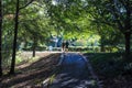 A long rough black footpath through the park with a couple walking along the path covered with fallen autumn leaves Royalty Free Stock Photo