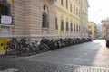 A long row of bicycles and scooters stand in the old town square near the building.